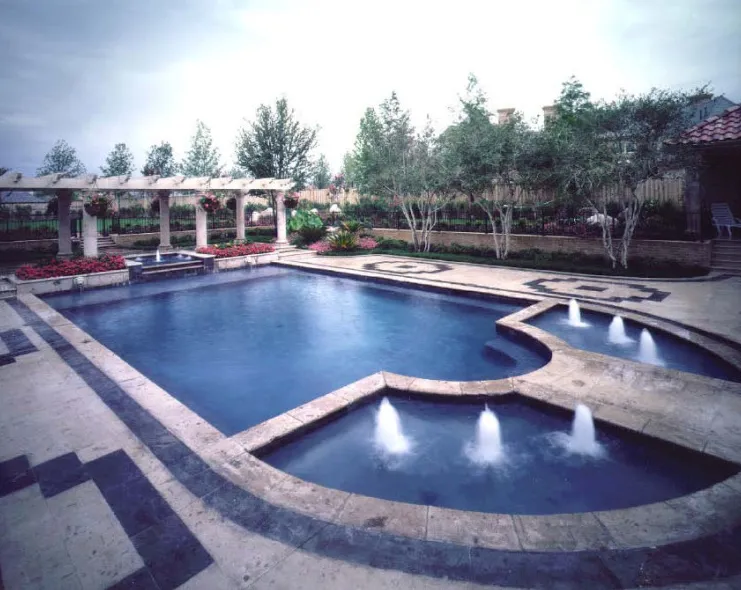Formal geometric pool with water jet fountains, decorative mosaic tile border, and white pergola in a landscaped backyard in Lakehurst, NJ by Gorlin Pools