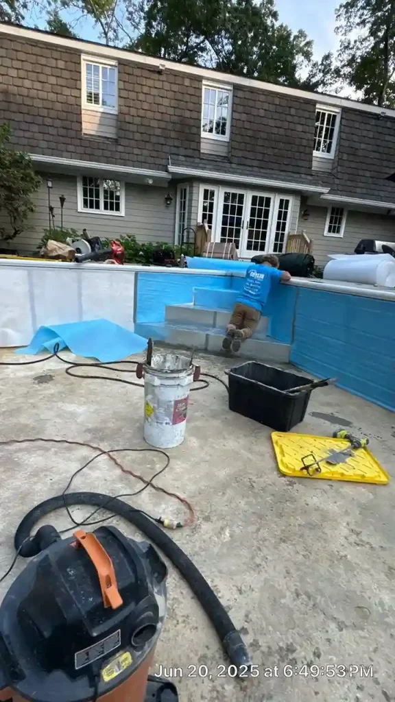 Gorlin Pools technician installing a blue vinyl liner inside an empty rectangular pool at a residential home in Lakehurst, NJ