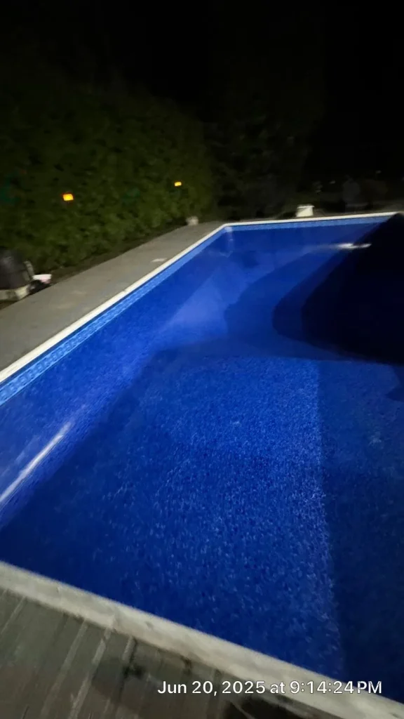 Corner angle view of a newly installed blue vinyl liner in an empty rectangular pool being filled at night in Lakehurst, NJ by Gorlin Pools