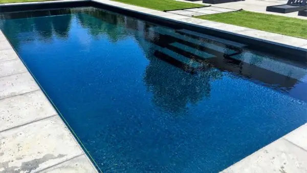 Rectangular fiberglass pool with dark finish, wide built-in entry steps, and modern concrete coping surround in Lakehurst, NJ by Gorlin Pools