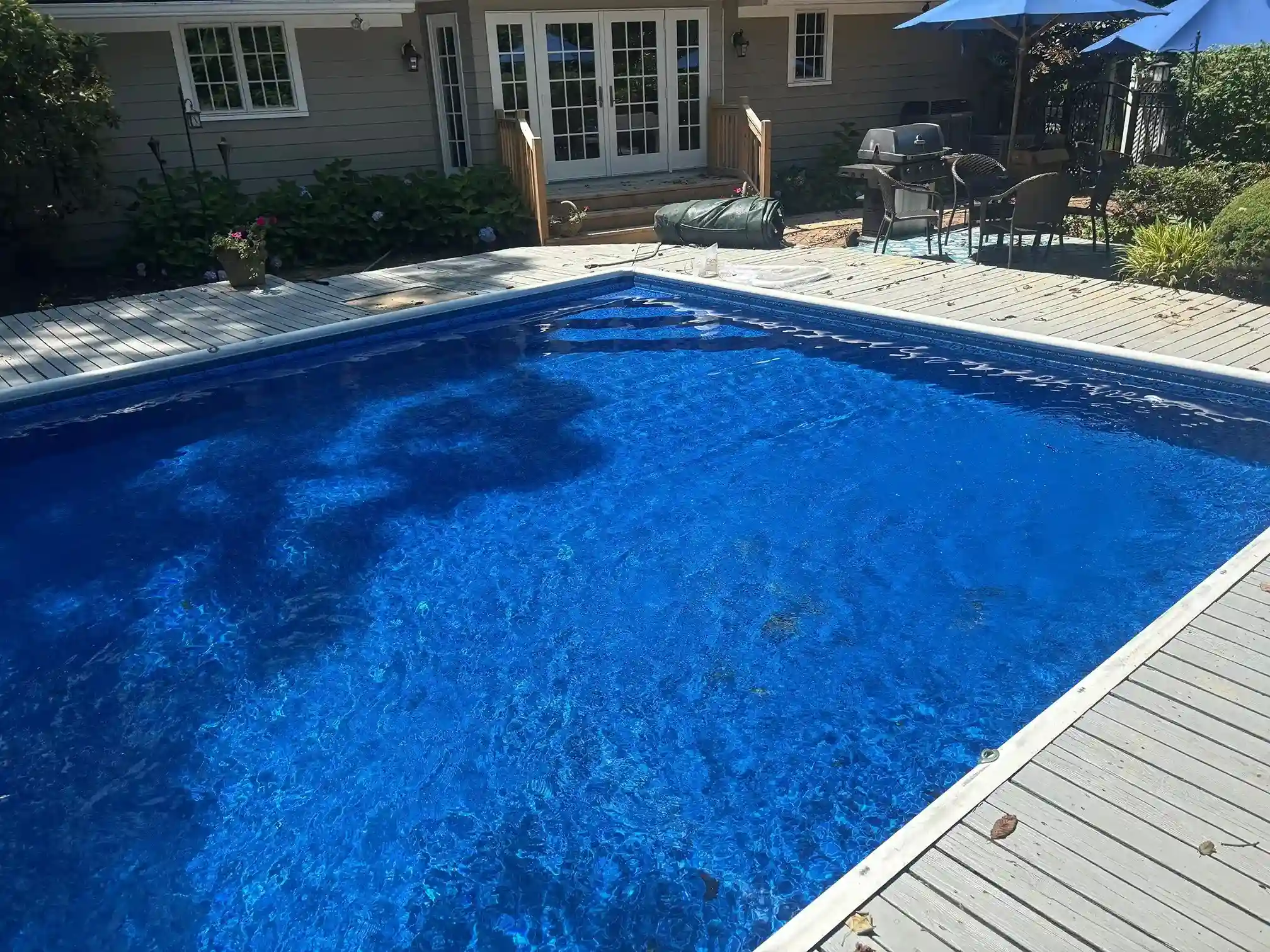 Rectangular in-ground pool with dark blue vinyl liner and wood deck surround at a residential home in New Jersey by Gorlin Pools