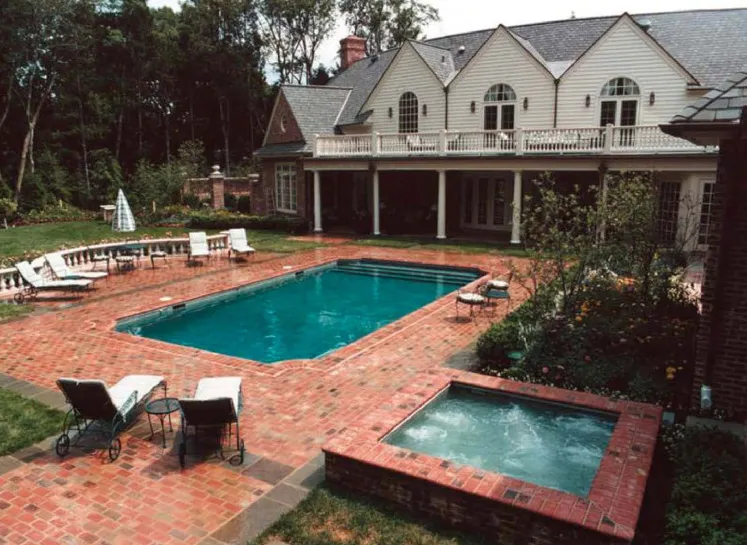 Rectangular pool with raised brick spa, brick paver patio, and lounge chairs at a large estate home in Lakehurst, NJ by Gorlin Pools