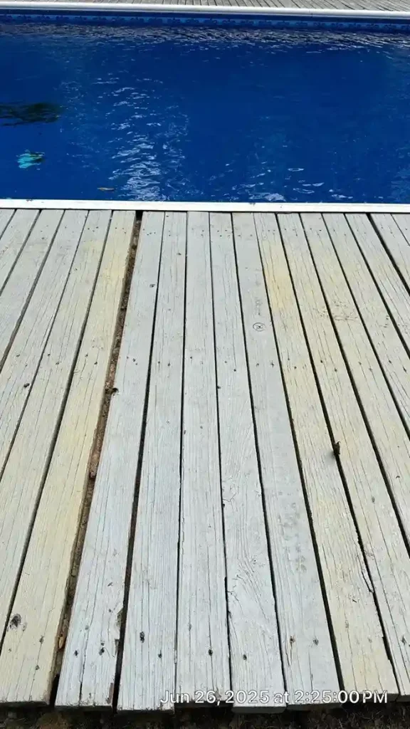 Close-up of a weathered and split wood deck plank at the edge of a pool showing signs of aging and wear in Lakehurst, NJ by Gorlin Pools