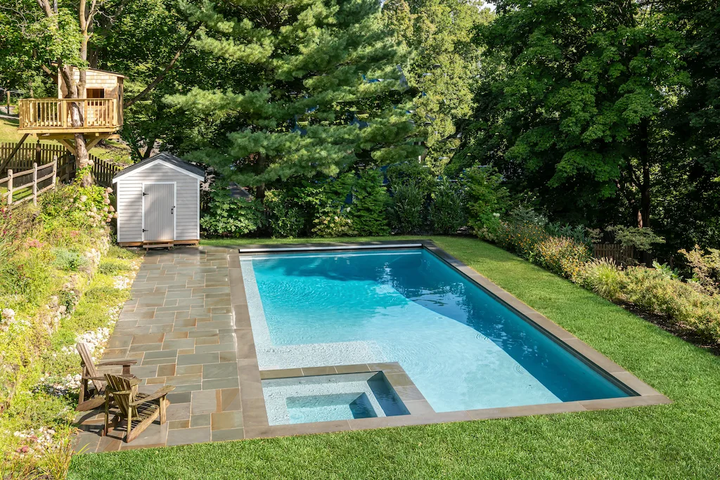 Rectangular pool with inset spa, automatic cover, and bluestone patio beside a treehouse in Lakehurst, NJ by Gorlin Pools