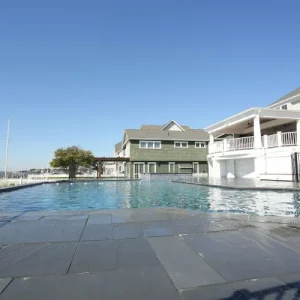 Commercial pool with bluestone deck and open waterfront marina view next to a coastal resort building in Lakehurst, NJ by Gorlin Pools