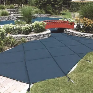 Freeform pool with dark mesh safety cover installed, decorative red arched bridge, and stone wall garden in Lakehurst, NJ by Gorlin Pools