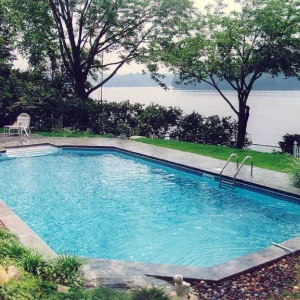 Grecian-shaped in-ground pool with stainless steel handrail and scenic lakefront water view in Lakehurst, NJ by Gorlin Pools