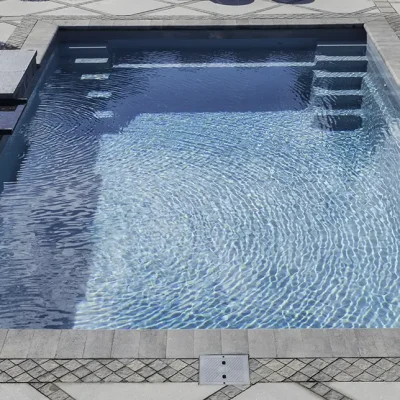 Rectangular gunite pool with attached square spa, built-in steps, and decorative mosaic paver border patio in Lakehurst, NJ by Gorlin Pools