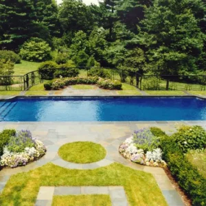 Rectangular in-ground pool with bluestone coping, wrought iron fence, and manicured flower beds in New Jersey by Gorlin Pools