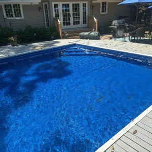 Rectangular in-ground pool with dark blue vinyl liner and wood deck surround at a residential home in New Jersey by Gorlin Pools