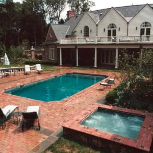 Rectangular pool with raised brick spa, brick paver patio, and lounge chairs at a large estate home in Lakehurst, NJ by Gorlin Pools