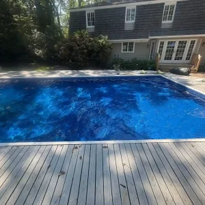 Rectangular pool with dark blue vinyl liner being filled next to a wood deck and shingle colonial home in Lakehurst, NJ by Gorlin Pools